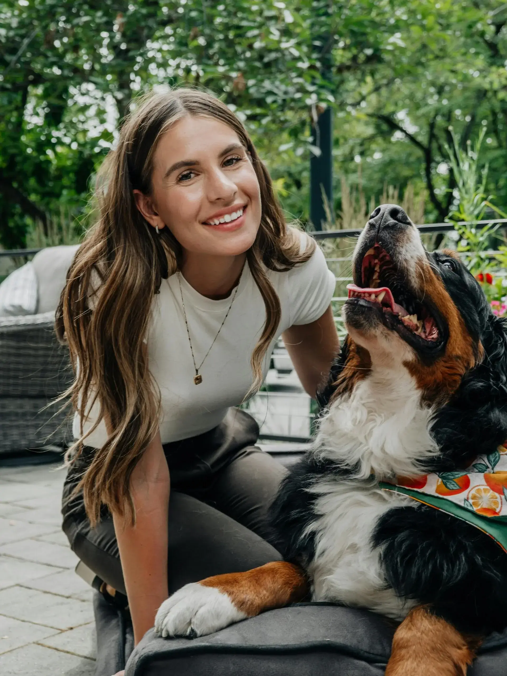 Sydney smiling outdoors with a happy Bernese Mountain Dog